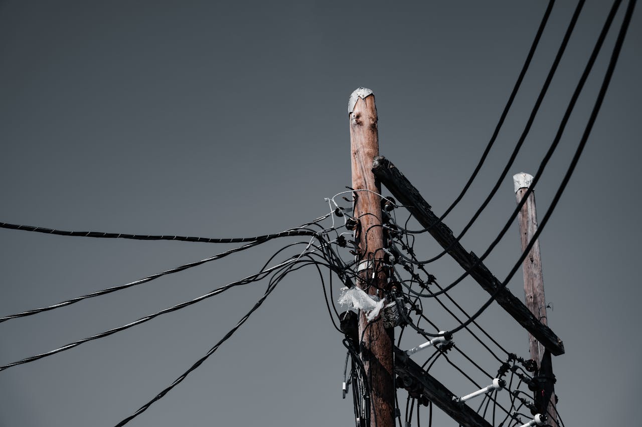 our-services-3 Low angle shot of wooden utility poles with power lines against a gray sky in Orlando, FL.
