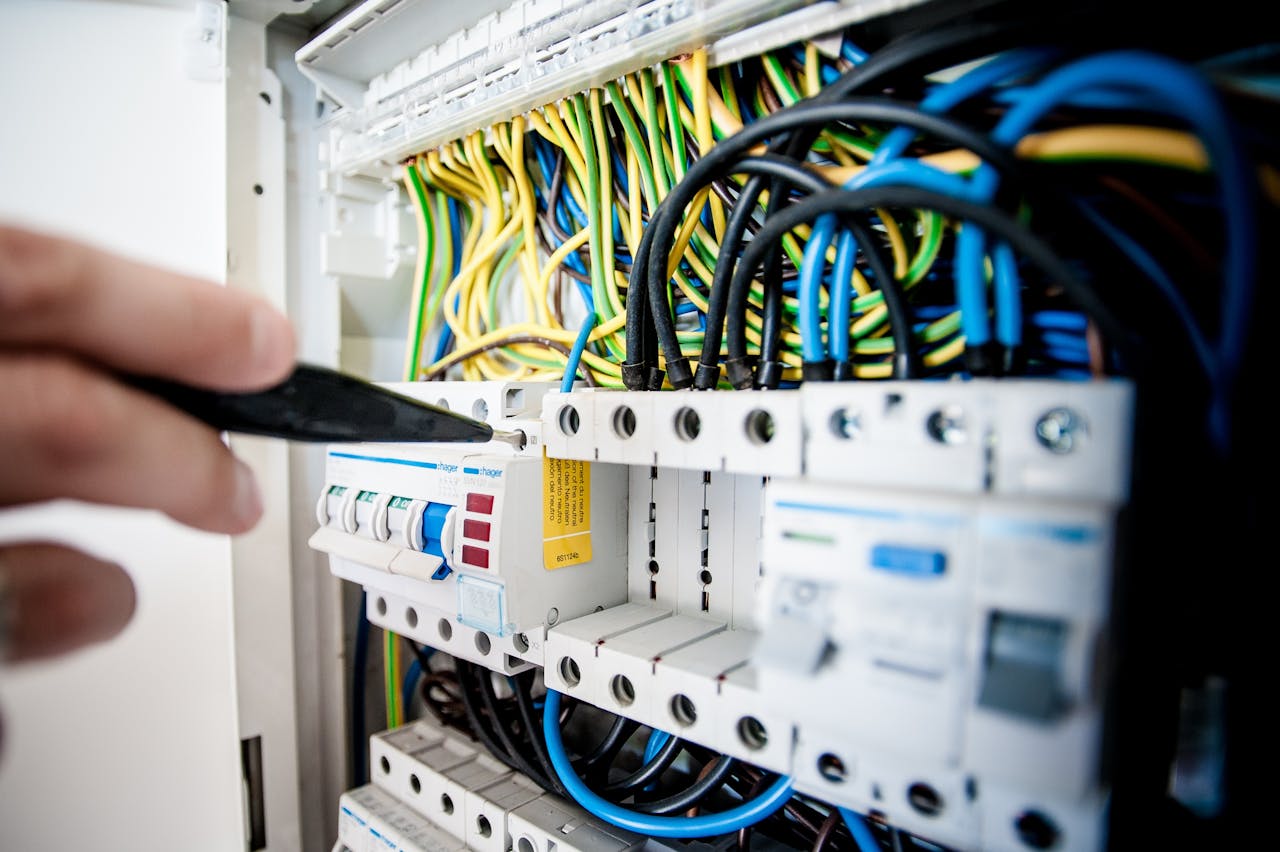 why-choose-us Hand of electrician working on a circuit breaker panel with colorful wires, ensuring safe electrical connections.