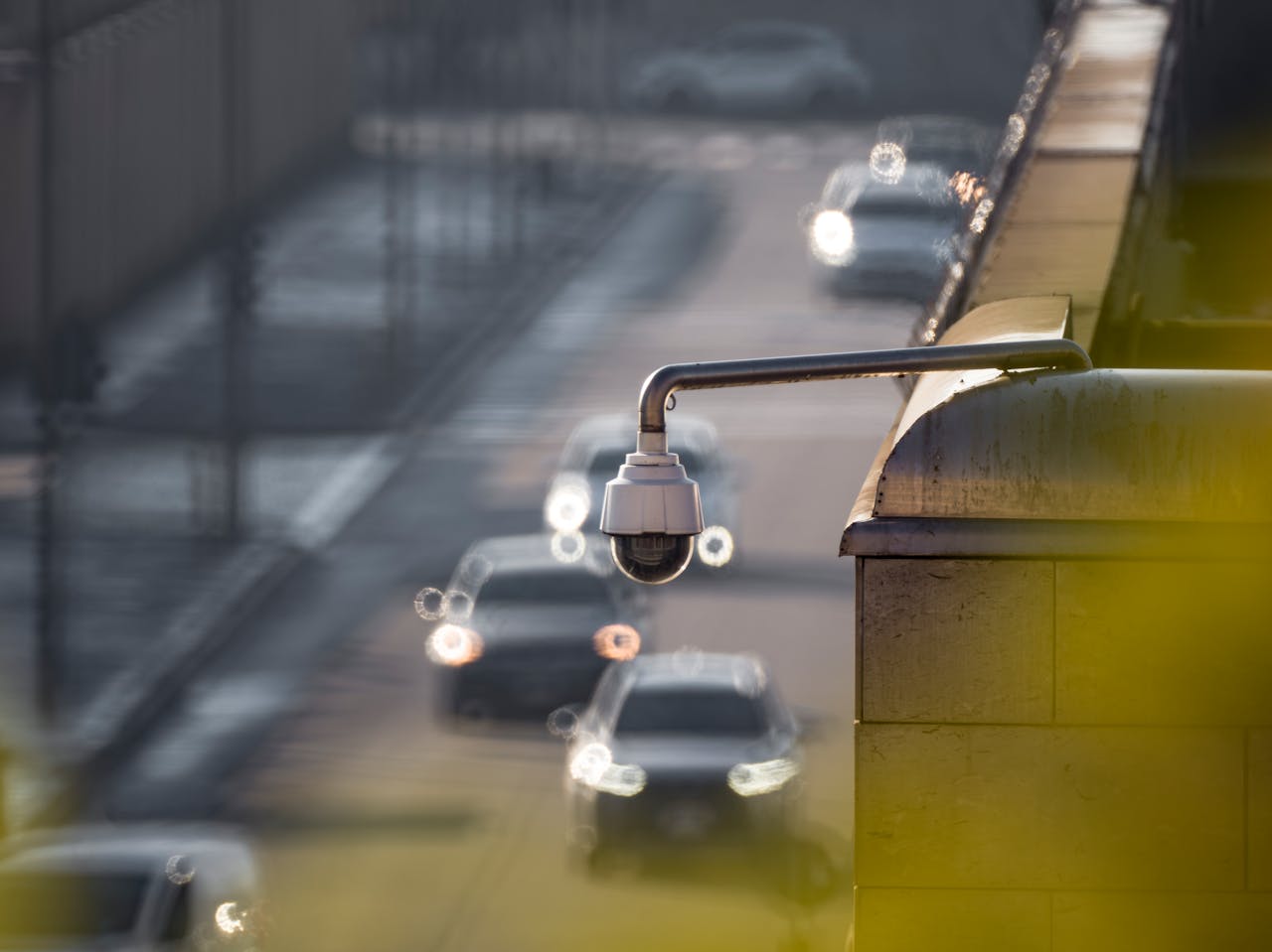 about-02 CCTV camera monitoring city traffic on a busy road with blurred vehicles in the background.