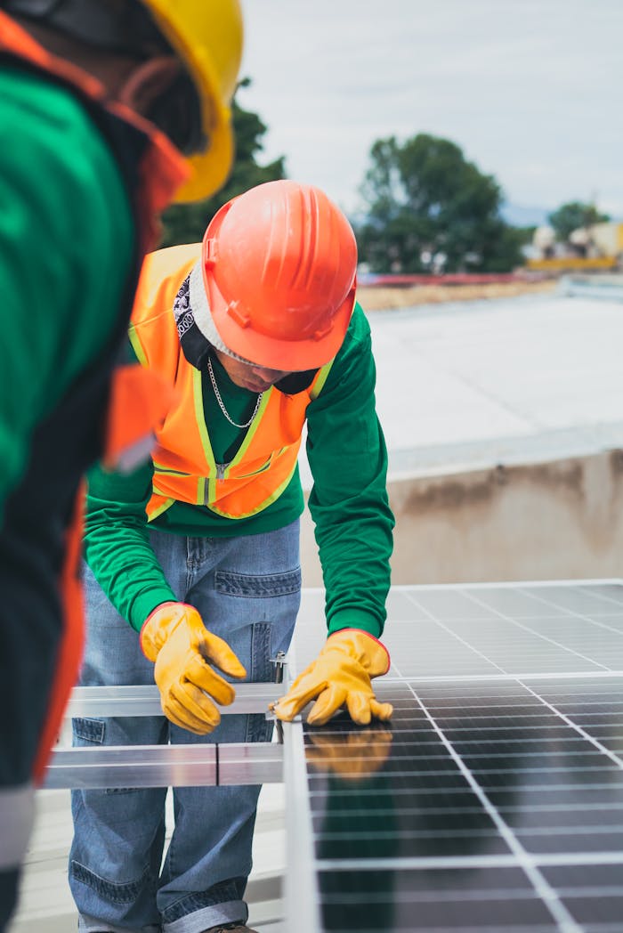 gallery-1 Worker in safety gear installing solar panels on a rooftop.