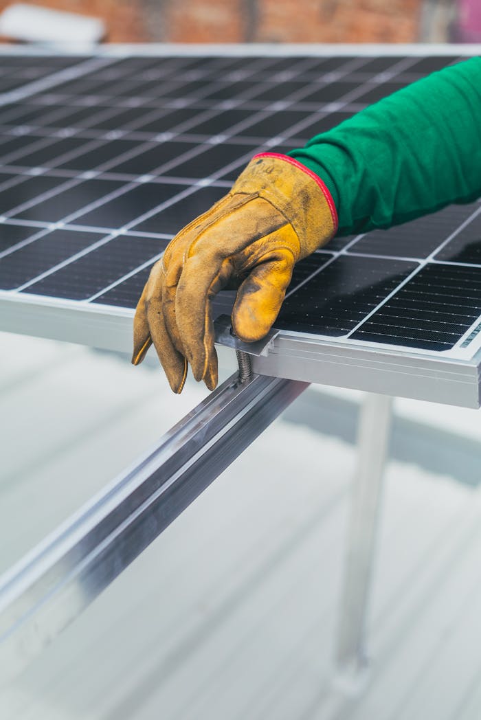 contact-img Close-up of a worker's hand in protective glove installing a solar panel.