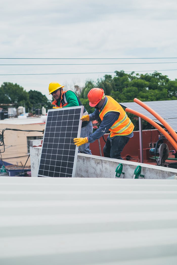 services-01 Two workers in safety gear installing solar panels on a rooftop for sustainable energy.